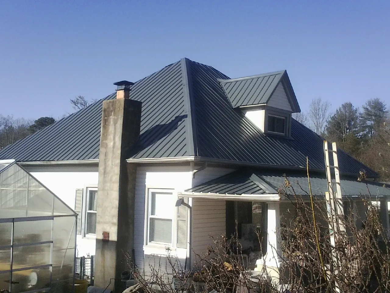 Dark blue standing seam metal roof on a white farmhouse with dormer — Slate & Tile Roof Repair by Roofing Brothers in Fort Monroe