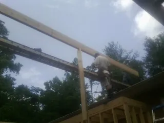 Carpenter setting a ridge beam over a new addition frame — Ice Dam Removal by Roofing Brothers in Fort Monroe