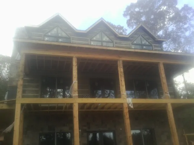 Dormers and porch framing on a large log home under construction — Roof Coating work by our crew in Fort Monroe