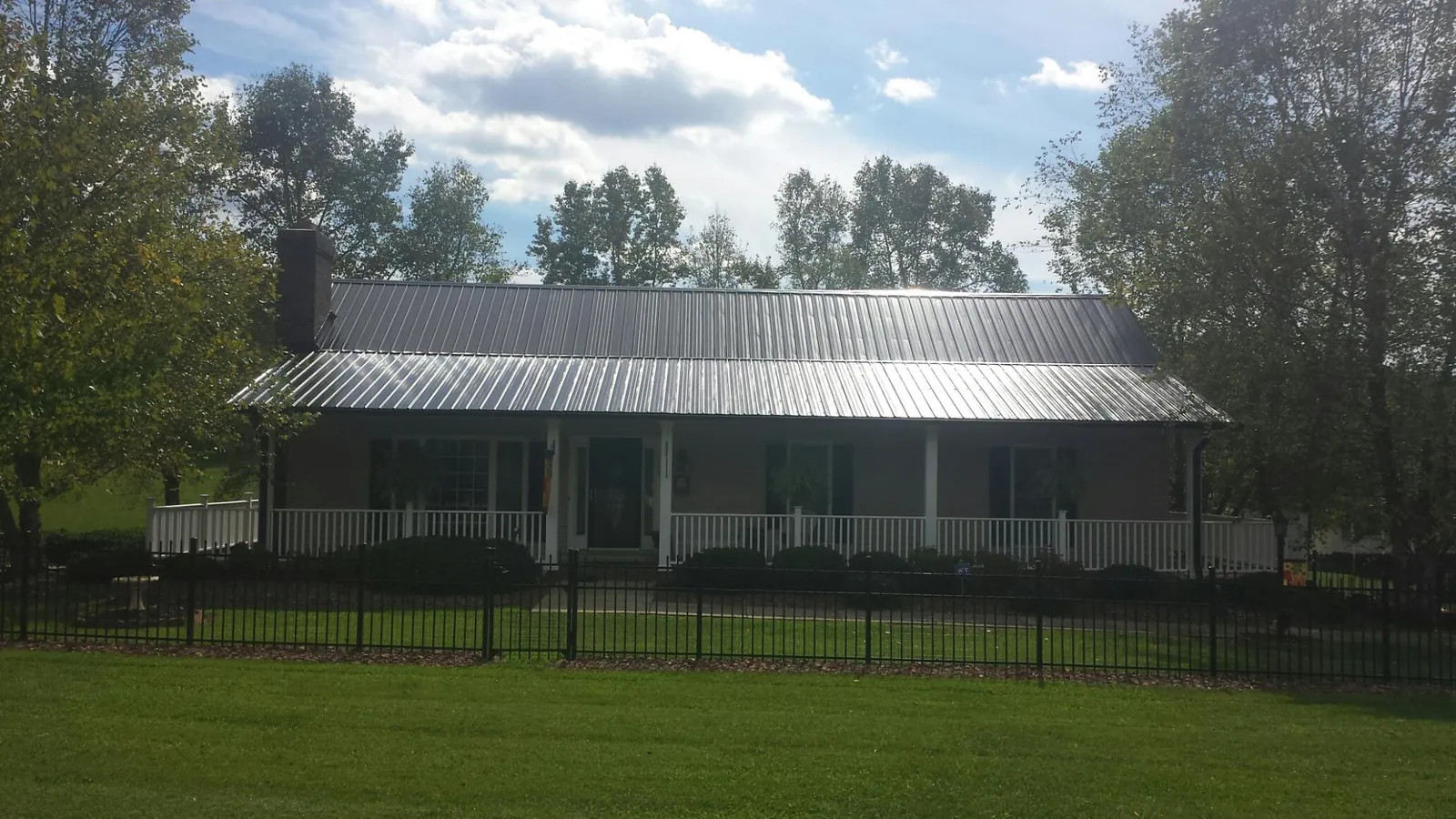 Gray metal roof on a brick ranch with a full width front porch — Gutter Guard Installation work by our crew in Fort Monroe