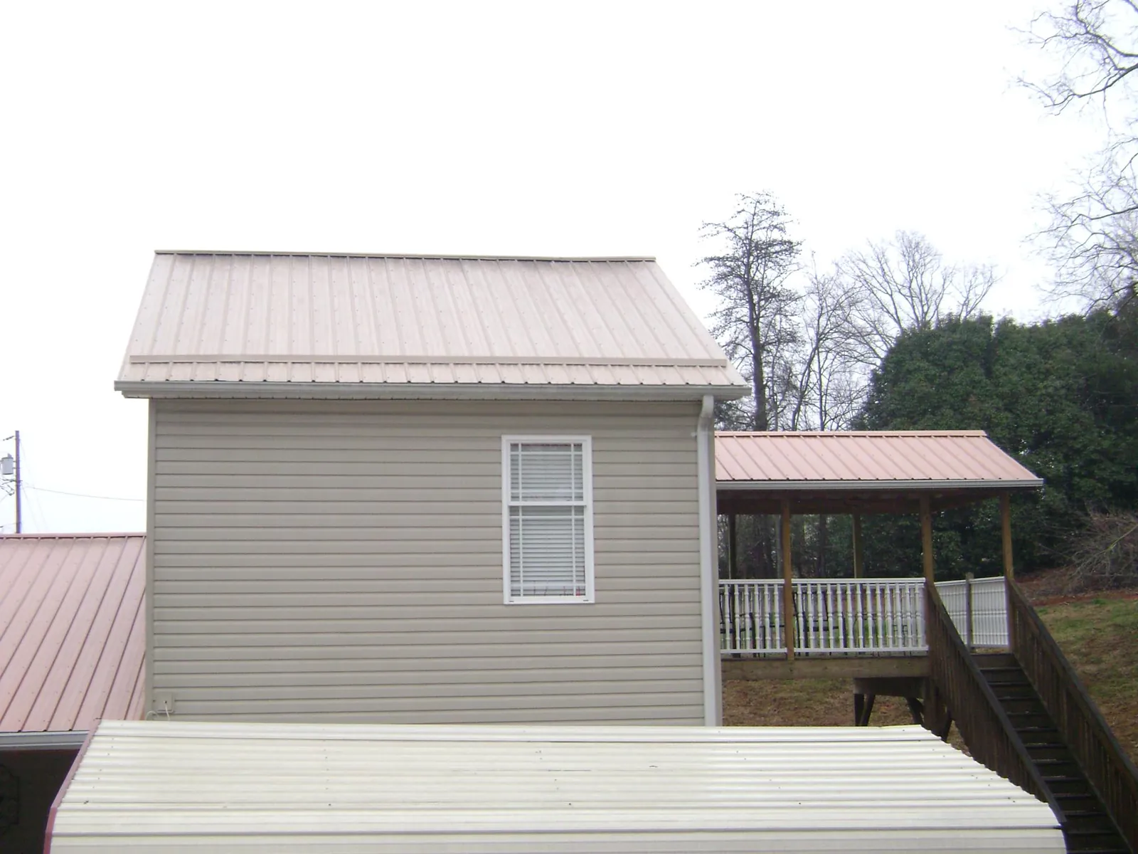 Tan metal roofs on a two story addition and attached porch in Fort Monroe
