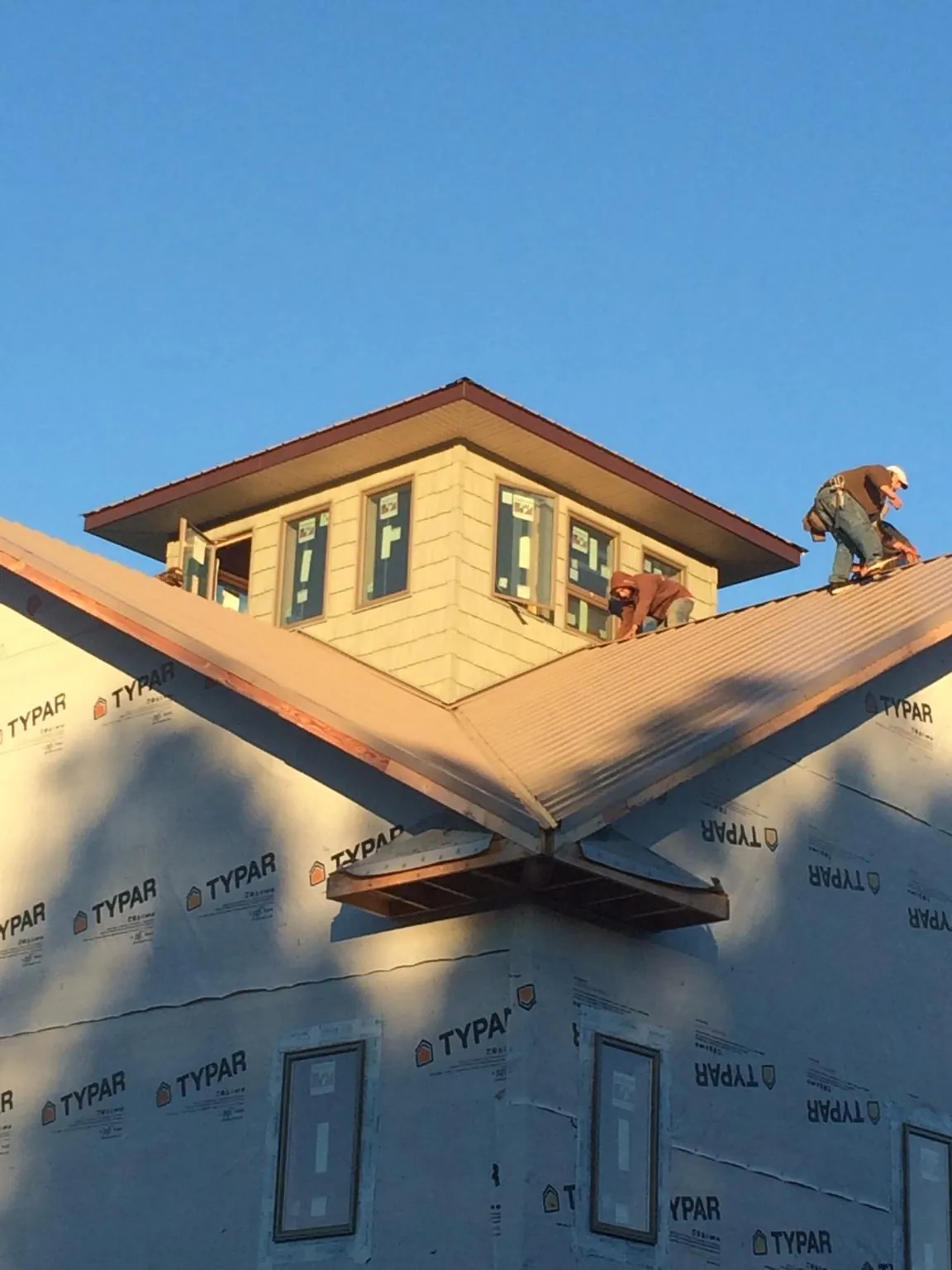 Roofers working around a rooftop cupola on a new metal roof at sunset — Roof Waterproofing in Fort Monroe by Roofing Brothers